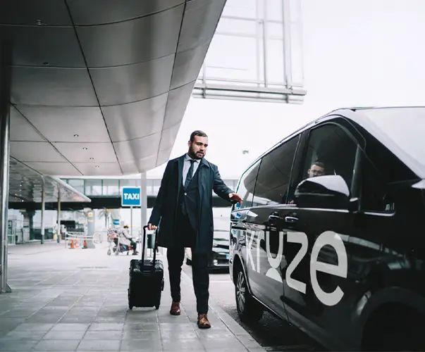 Business traveler entering Kruze airport taxi with luggage